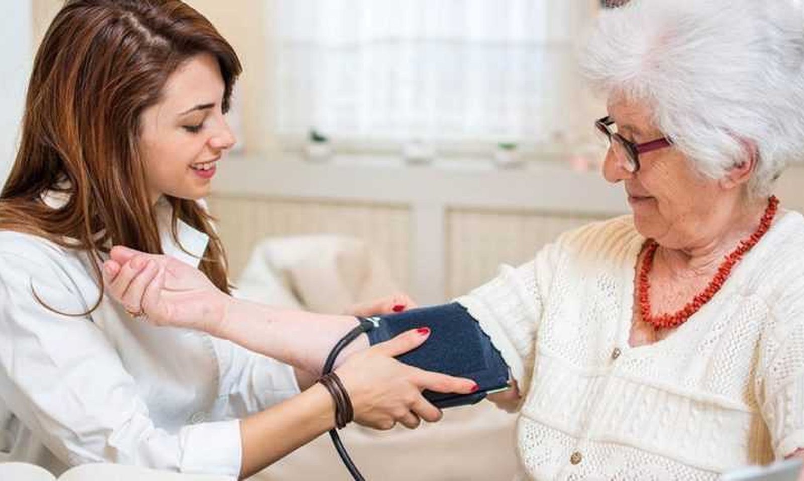 Nurse checking a client's blood pressure at home